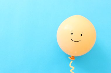 Mavi zemin üzerinde mutlu yüzü olan balonun üst görünümü