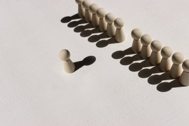 Farklı düşünme ve yaratıcılığı bulma imajını kavra. Tahta figürler duvar oluştururken, bir kişi farklı yönleri işaret ediyor.