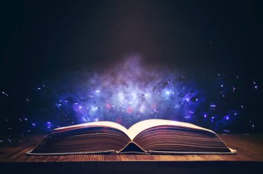 Tahta masanın üzerinde parıltılı kaplamalı açık antik kitap görüntüsü