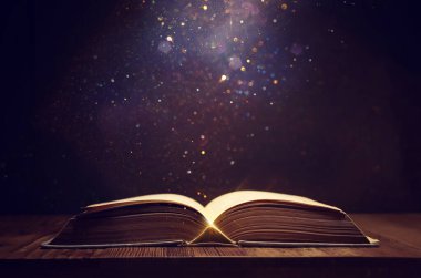 Tahta masanın üzerinde parıltılı kaplamalı açık antik kitap görüntüsü