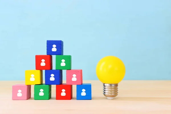 Education and human resource concept image. Creative idea and innovation. light bulb metaphor over blue background, wooden cubes and people icons