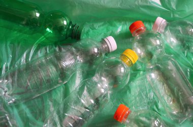 Beyaz zemin üzerinde yeşil geri dönüşüm kutusu olan plastik şişeler.