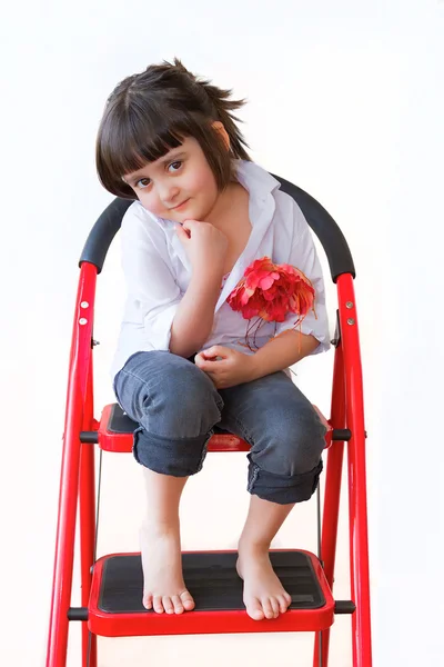 Het mooie meisje zit op een rode ladder — Stockfoto