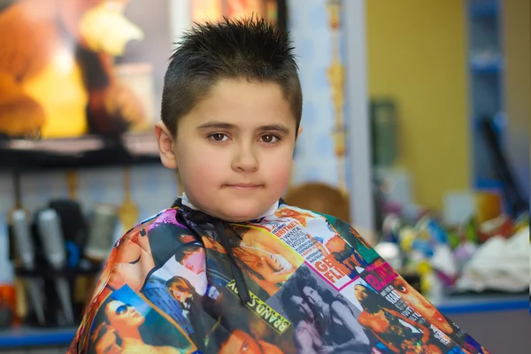 Garçon avec une nouvelle coupe de cheveux dans un salon de coiffure se trouve — Photo