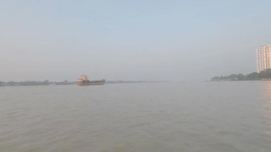 Konteynır gemisi Khidirpur limanından ayrıldıktan sonra Ganj Nehri 'nden geçiyor. Görüntü, feribot yolculuğundan günbatımında açık gökyüzüne doğru çekildi. Kolkata Hindistan Asya