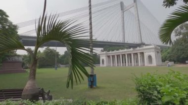 Arka planda Howrah Köprüsü 'ne karşı Prinsep Ghat mimari peyzajı ve Yunan veya Gotik yapısı ile ünlü ön planda park. Kolkata Batı Bengal Hindistan Asya Pasifik 21 Ekim 2021