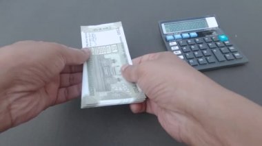 İnsan eli, hesap makinesine ve masaya yerleştirilmiş bir kaleme karşı 500 rupi Hindistan parası sayıyor. Yüksek açı. Kapatın. Bankacılık İşletme Finans Arkaplanı.
