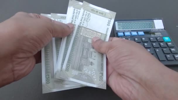 人类的手在桌上用计算器和笔数新的500卢比印度卢比钞票 高角镜 靠近点银行业金融背景 — 图库视频影像