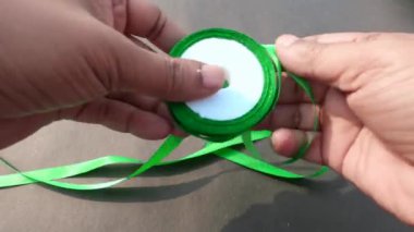 Gri arka planda koyu yeşil yuvarlanan saten kurdelenin bir kısmını kapat. Masaya bir nesne yerleştir ve yerleştir. İş düzenleme kavramı.