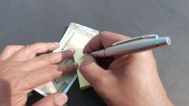 Masadaki Hint parasına karşı aylık harcamalar üzerine el yazısını kapat. Yüksek Açı Görünümü.