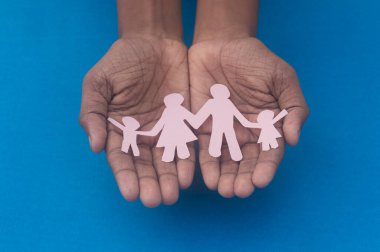 Aile figürünün el ele tutuşması. Aile içi şiddete, sağlık hizmetlerine ve tıbbi geçmişe karşı Dünya Sağlık Günlüğü Koruma Programı. Koruyucu aile, evsiz desteği ve sosyal uzaklık kavramı.