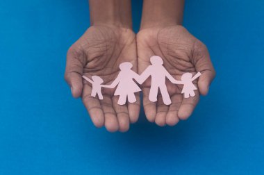 Aile figürünün el ele tutuşması. Aile içi şiddete, sağlık hizmetlerine ve tıbbi geçmişe karşı Dünya Sağlık Günlüğü Koruma Programı. Koruyucu aile, evsiz desteği ve sosyal uzaklık kavramı.