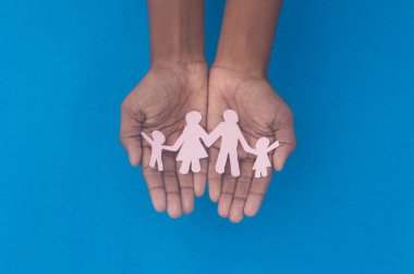 Aile figürünün el ele tutuşması. Aile içi şiddete, sağlık hizmetlerine ve tıbbi geçmişe karşı Dünya Sağlık Günlüğü Koruma Programı. Koruyucu aile, evsiz desteği ve sosyal uzaklık kavramı.