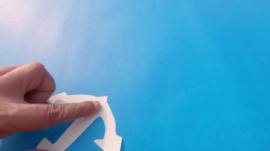 İzole edilmiş mavi arka plana beyaz çapa yerleştiriliyor. Denizcilik teması. Boşluğu Kopyala.