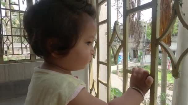 Μικρό Χαριτωμένο Αγοράκι Που Κοιτάει Από Παράθυρο Στο Μπαλκόνι Περίεργο — Αρχείο Βίντεο