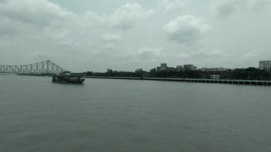a ferry boat sailing on Hooghly river leaving Howrah bridge in behind. Footage captured from Babu Ghat Ferry Terminal. Kolkata West Bengal India South Asia Pacific