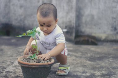 Cute Little baby boy with Flower tub loves to play in the dirt.