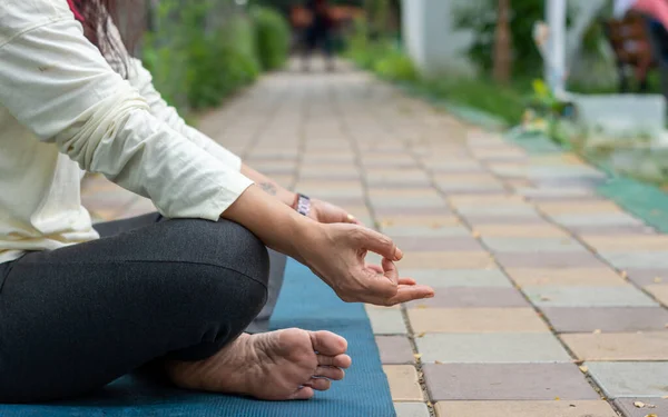 Close up woman mudra hand gesture doing yoga relaxing in lotus position sitting on mat. outdoors. Practicing meditation in nature. Background Photo.