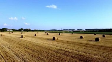 Drone flies over a field with haystacks