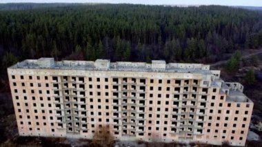 Drone takeoff over a large unfinished house on the edge of the forest