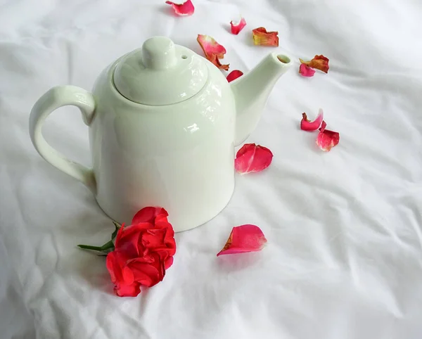 Biały czajnik i płatki róż na białym tle — Zdjęcie stockowe