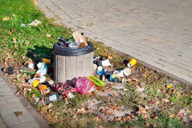 Çöp konteynırı. Çöp tenekesi. Çöp, sokaktaki çöp kutusunun etrafına saçılmış. Şehirde atık geri dönüşümü kavramı. 