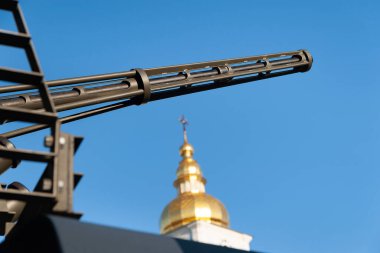 Kilisenin arka planına karşı otomatik bir topun namlusu. Kiev 'de askeri teçhizat sergisi. Modern askeri teknoloji. Ukrayna. Kiev. 15 Ekim 2021