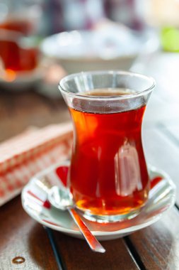 Türk çayı. Kafedeki bir masada bir bardak çay. Geleneksel Türk bardağında çay yakın plan. Seçici yumuşak odak.