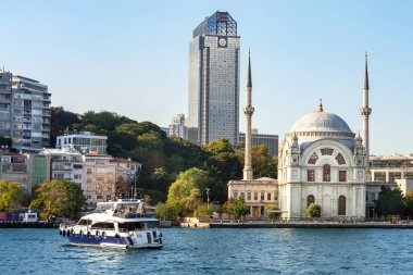 Bir gökdelenin arka planında Dolmabahçe Camii. İstanbul 'daki Boğaz' daki Dolmabahçe Camii yakınlarında bir tekne. İstanbul. Türkiye - 09.25.2021.