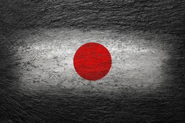 Japan flag. Japanese flag is painted on a black stone. Creative background.