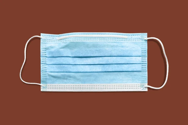 Medical mask. Disposable surgical mask. Protection against respiratory infections. Isolate on brown background. Danger of a viral infection. Health care and medical concept