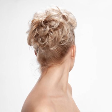 Genç bir kadının geçmişe bakış açısı. Çıplak, genç, sarışın kadın. Kıvırcık saçlı. Şık bir saç stili. Hafif bir arkaplanda izole edilmiş