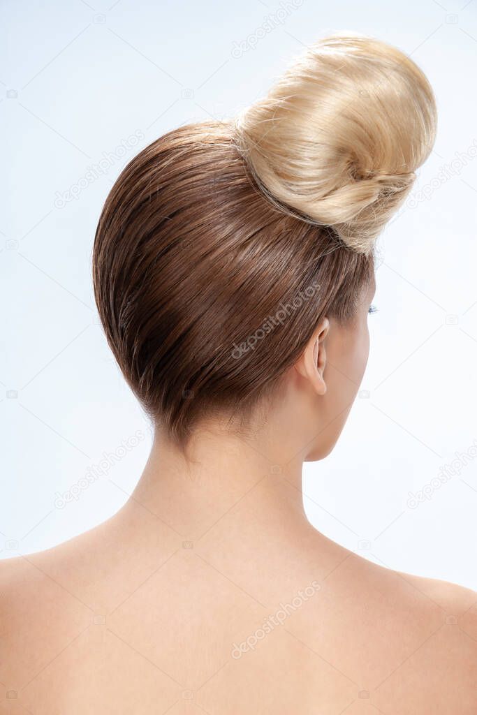 Back view of young woman. Portrait of a naked young white woman. Dark hair. Stylish hairstyle. Isolated on a light background