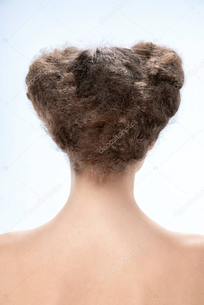 Back view of young woman. Nude young caucasian brunette woman. Dark hair. Stylish hairstyle. Isolated on a light background