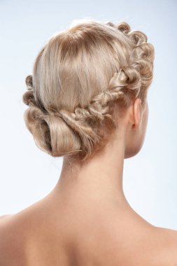 Genç bir kadının geçmişe bakış açısı. Çıplak beyaz bir sarışının portresi. Açık kıvırcık saçlı. Şık bir saç modeli. Hafif bir arkaplanda izole edilmiş