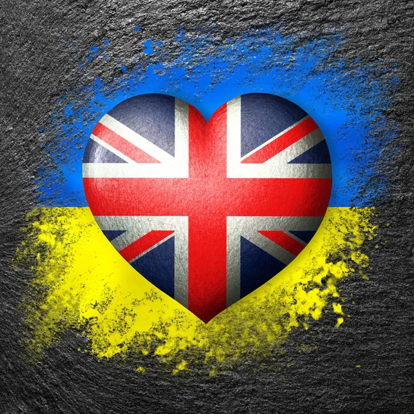 Flags of Ukraine and Great Britain. Flag heart on the background of the flag of Ukraine painted on a stone. The concept of protection and solidarity. Military and humanitarian assistance.