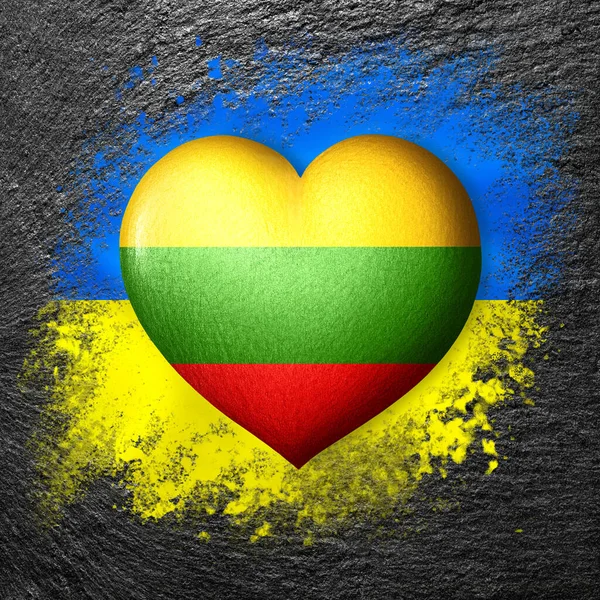 Flags of Ukraine and Lithuania. Flag heart on the background of the flag of Ukraine painted on a stone. The concept of protection and solidarity. Military and humanitarian assistance.