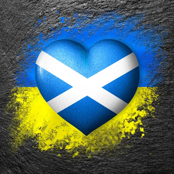 Flags of Ukraine and Scotland. Flag heart on the background of the flag of Ukraine painted on a stone. The concept of protection and solidarity. Military and humanitarian assistance.