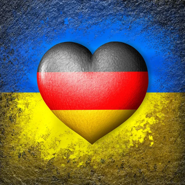 Flags of Ukraine and Germany. Flag heart on the background of the Ukrainian flag painted on a stone. The concept of protection and solidarity. Military and humanitarian assistance.