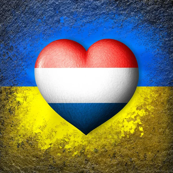 Flags of Ukraine and Netherlands.Flag heart on the background of the Ukrainian flag painted on a stone. The concept of protection and solidarity. Military and humanitarian assistance.