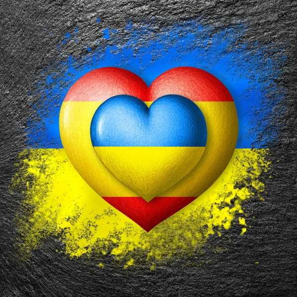 Flags of Ukraine and Spain. Two hearts in the colors of the flags on the flag of Ukraine painted on stone. Protection, solidarity and help concept. Cooperation of countries.
