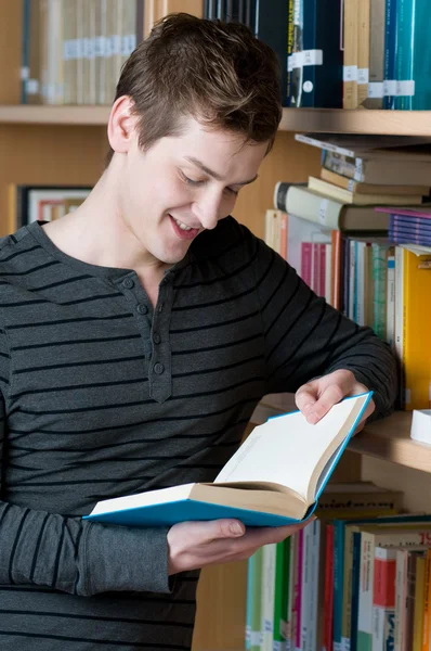 Glücklicher Student liest Buch in einer Bibliothek — Stockfoto