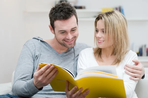 Young couple reading magazine — Stock Photo, Image