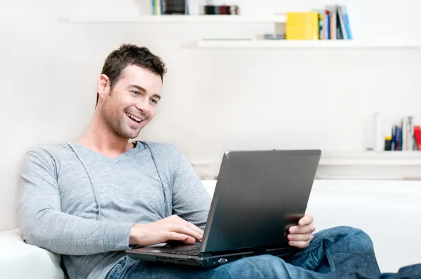 Smiling young man working on laptop — Stock Photo, Image