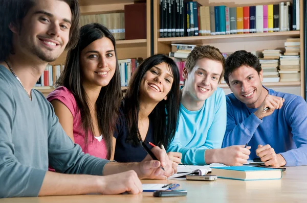 Sonriente grupo de estudiantes en una biblioteca Fotos de stock libres de derechos