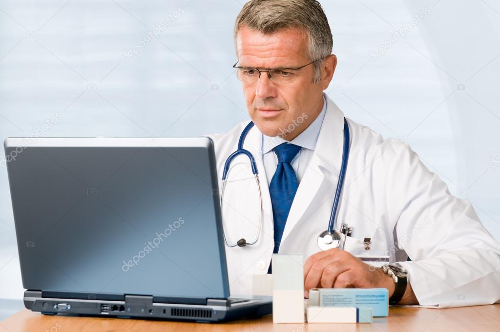Mature doctor working on laptop