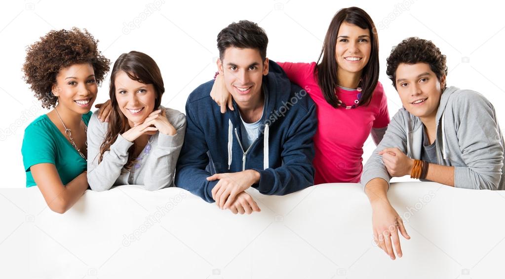 Happy multi ethnic group of friends showing blank billboard