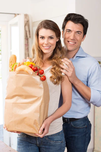 Casal com saco de supermercado na cozinha — Fotografia de Stock