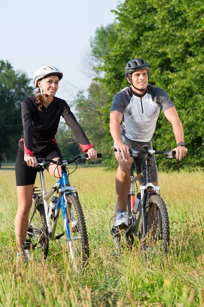 Casal jovem com bicicleta no prado — Fotografia de Stock