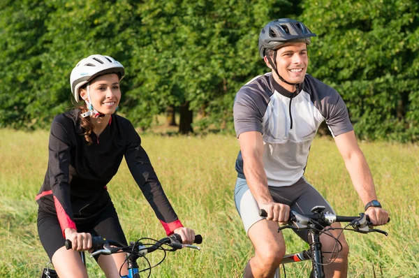 Ungt par ridning cykel i äng — Stockfoto